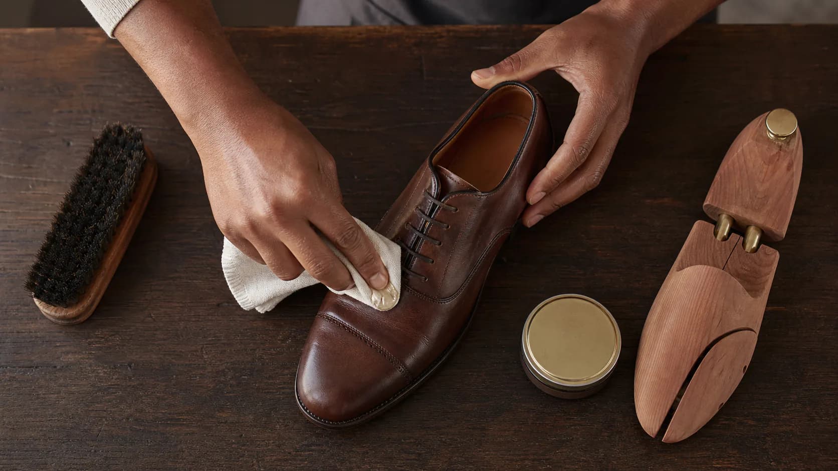 Leather care brushes, cloth and cream beside a brown shoe